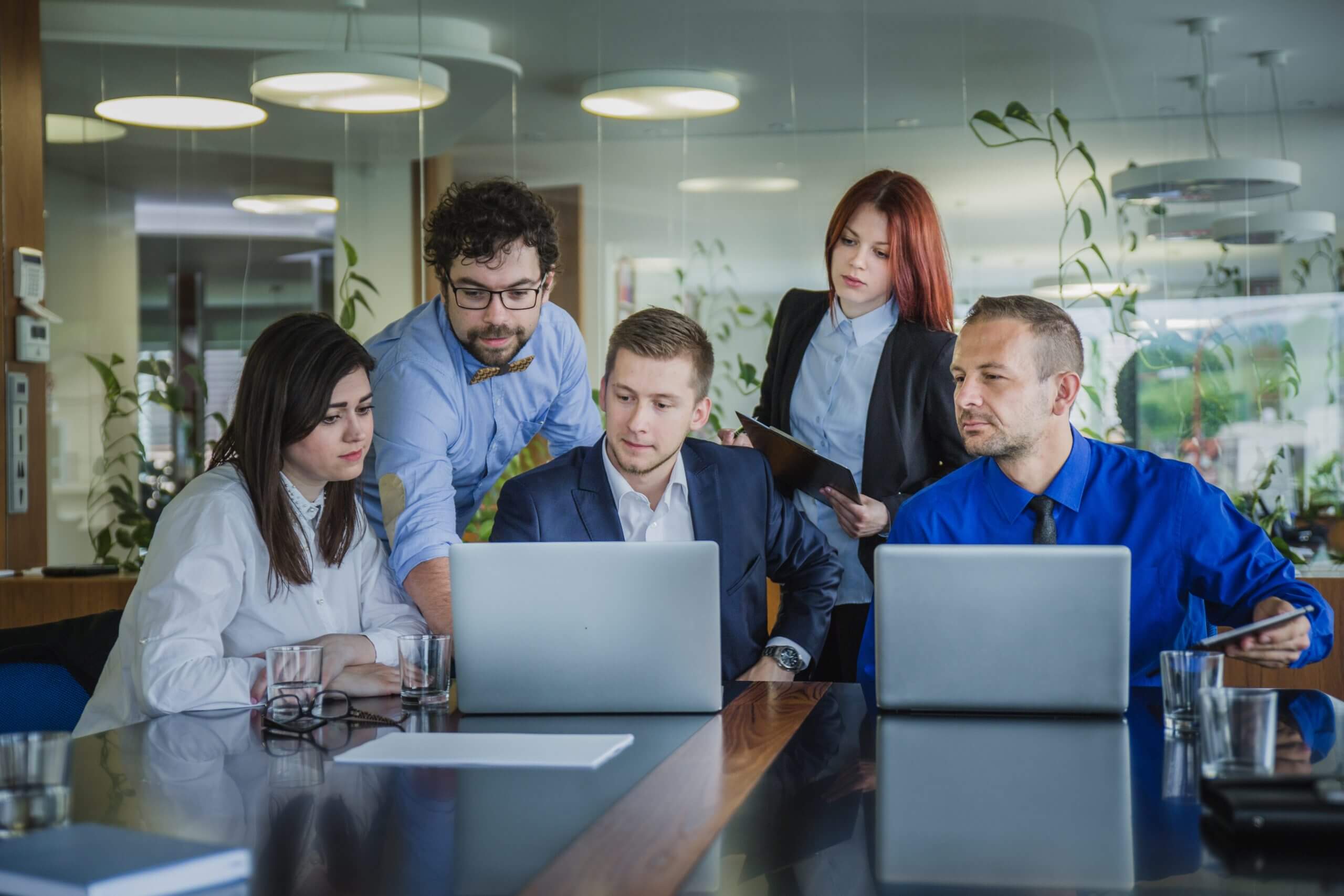 Réunion d’équipe en entreprise autour d’ordinateurs pour discuter de stratégie collaborative.