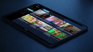 Tablette affichant l’interface de l’application Mondial TV avec une grille de chaînes et des aperçus de programmes, sur un fond bleu sombre.